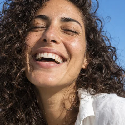 Demonstration portrait of a laughing woman against a blue sky